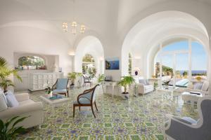 ein großes Wohnzimmer mit weißen Möbeln und Fenstern in der Unterkunft Sina Flora in Capri