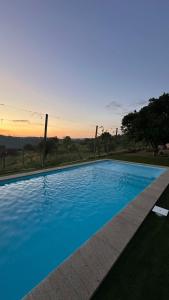 a blue swimming pool with a sunset in the background at Casa da Boavista in Amarante