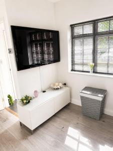 a white living room with a tv on the wall at The lodge in Rushbrooke