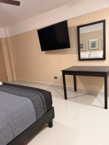 a bedroom with a bed and a desk and a television at Hotel Posada de Santiago in Tijuana