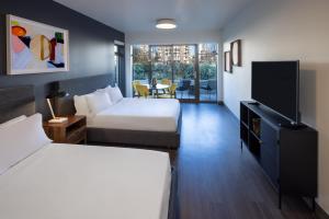 a hotel room with two beds and a flat screen tv at Revival English Bay, Vancouver in Vancouver