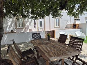 a wooden table and chairs under a tree at Cosy Country House in Cerro da Cova