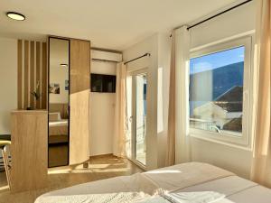 a bedroom with a bed and a large window at Modern Beachfront Apartment in Đenovići