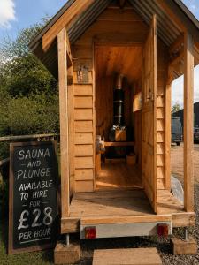 a small wooden dog house with a sign in front at Hinton land glampsite in Peterchurch