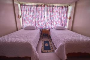 zwei Betten in einem kleinen Zimmer mit Fenster in der Unterkunft Hotel Los Alamos in Riobamba