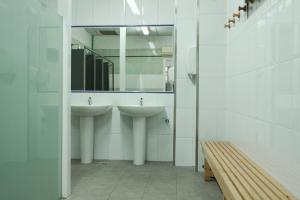 a bathroom with two sinks and a mirror and a bench at Augas Quentes Hostel in Ourense +80 photos