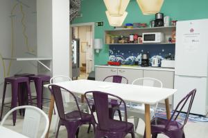 a kitchen with a white table and purple chairs at Augas Quentes Hostel in Ourense