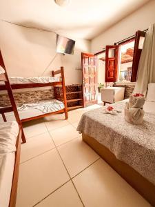 a bedroom with two bunk beds and a living room at Pousada Timbalada in Morro de São Paulo