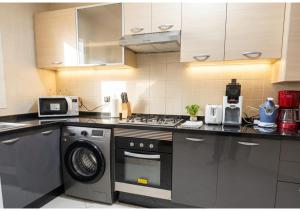 a kitchen with a stove and a washing machine at L'Olivier à Marina Golf Vue sur Piscine, Wi-Fi et Clim in Asilah