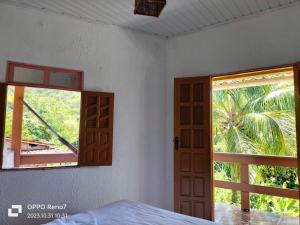 a bedroom with an open door and a window at Pousada pôr do sol in Cairu