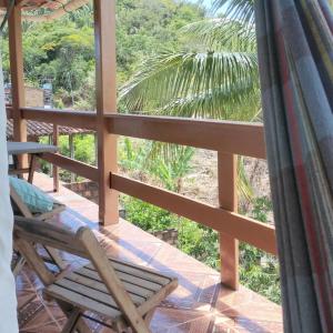 a porch with a chair and a palm tree at Pousada pôr do sol in Cairu