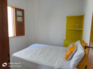 a small bedroom with a bed with a yellow shelf at Pousada pôr do sol in Cairu