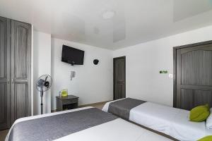 a hotel room with two beds and a flat screen tv at Hotel Exito La 21 in Pereira