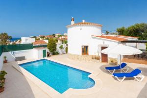 a villa with a swimming pool and two chairs and an umbrella at Villa Maria Large Private Pool AC WiFi in Cala en Porter