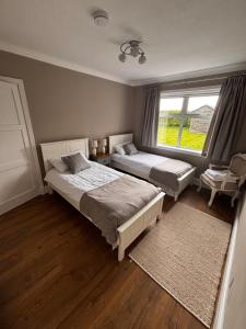 a bedroom with two beds and a window at 1 Shawsmuir Cottage in Thornhill