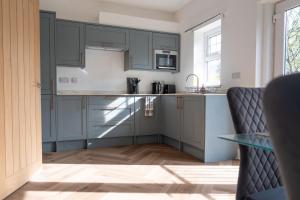 a kitchen with blue cabinets and a glass table at 2 BR Apartment- Private Parking in Newport +9 photos