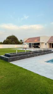 a building with a swimming pool next to a grass field at Groves Chalet in Rumays
