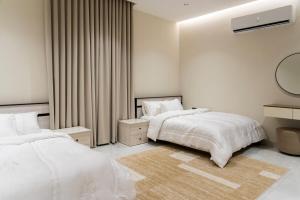 a white bedroom with two beds and a mirror at Groves Chalet in Rumays +104 photos