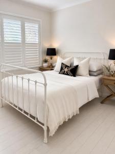 a white bedroom with a white bed with pillows at Avalon Beach Cottage- The Islander in Avalon