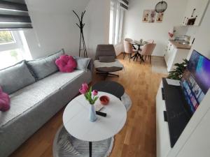a living room with a couch and a table with flowers on it at Jefimija Apartman Sokobanja in Soko Banja