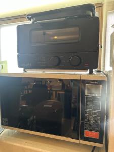 a microwave oven sitting on top of a shelf at Guest House "Ro"kumano in Shimonoseki