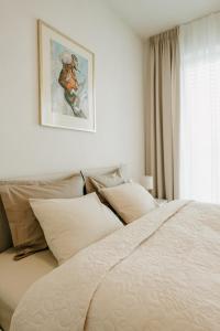 a bed with pillows and a picture on the wall at Aria Apartments in Prievidza