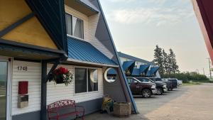 a building with cars parked in a parking lot at DC Lodge in Dawson Creek