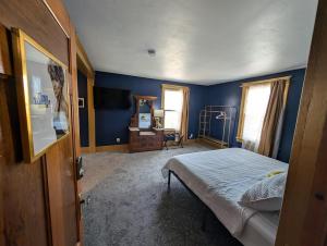 a bedroom with blue walls and a bed and a dresser at The Queen Hotel- Downtown Luxury in Sturgeon Bay