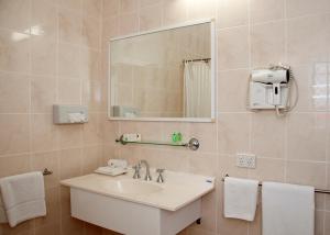 a bathroom with a sink, mirror, and towels at Jackaroo Motel in Mareeba