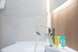 a bathroom sink with a faucet and toothbrushes at Skyview Suites in Lefkada