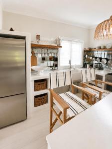 a kitchen with a stainless steel refrigerator and tables at Avalon Beach Cottage- The Islander in Avalon +16 photos