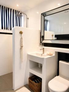 a white bathroom with a sink and a mirror at Avalon Beach Cottage- The Islander in Avalon