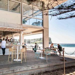 a group of people sitting at tables outside of a building at Avalon Beach Cottage- The Islander in Avalon