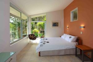 a bedroom with a bed and a large window at Nikau Apartments Waiheke Island in Onetangi