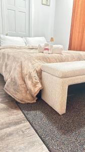 ein Bett mit einer Bettdecke und einer Bank in einem Schlafzimmer in der Unterkunft Charming space in Lynn