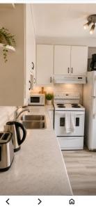 a white kitchen with a sink and a stove at Uottawa Private Room Meters away from Parliament Hill in Ottawa