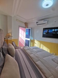 a bedroom with a large bed with a tv on the wall at Studio VIP - Bonamoussadi - Groupe électrogène - 2douches in Douala