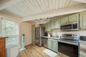 a kitchen with green cabinets and stainless steel appliances at Treehouse On Beech in Beech Mountain