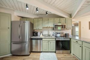 a kitchen with green cabinets and a stainless steel refrigerator at Treehouse On Beech in Beech Mountain