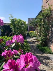 a garden with pink flowers and a brick building at Reeser Schatzkästchen in Rees