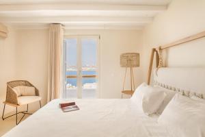 a bedroom with a bed and a chair and a window at Blue Diamond BESTOFMIKONOS in Ornos +17 photos