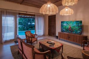 a living room with a television and a table and chairs at Villa Layan Hillside Residency with views and infinity pool in Amed in Ambat