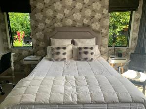 a bedroom with a large white bed with two windows at Private Retreat in Cambridge