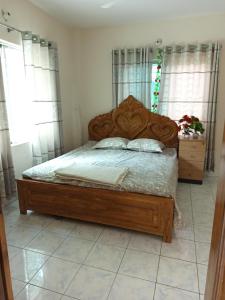 a bedroom with a wooden bed in a room with windows at Royal Palace in Dhaka