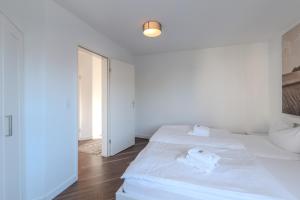 a white bed in a white room with a window at Marina Hafenblick 321 in Cuxhaven