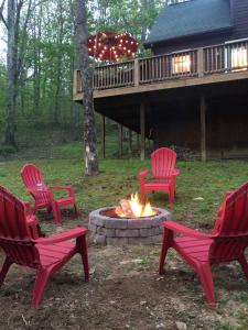 three red chairs around a fire pit in front of a cabin at Hidden Hawk in Seven Devils