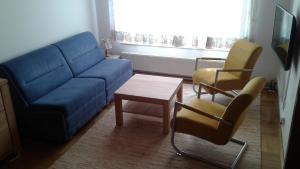 ein Wohnzimmer mit einem blauen Sofa und 2 Stühlen in der Unterkunft Ferienwohnung Lisbeth Ambra in Hermagor