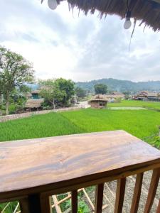a wooden table on a porch with a view of a field at Corn family homestay in Làng Me