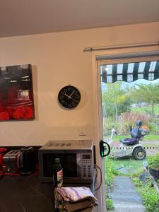 a kitchen with a microwave and a clock on the wall at MOWA Art House Apartment in Huonville