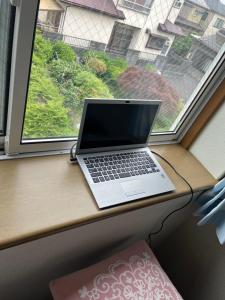 a laptop sitting on a window sill in front of a window at サンムーン鶴間 in Yamato